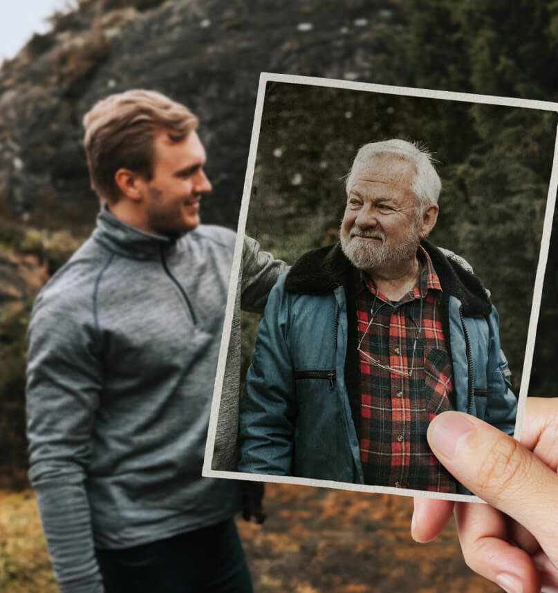 Two men appear to be hiking in rocky bushland. Looking closer, we notice the older man is actually not part of the scene, but is in fact just an aging photo held by an unseen viewer